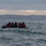 A small migrant boat in the English Channel with a rescue vessel nearby