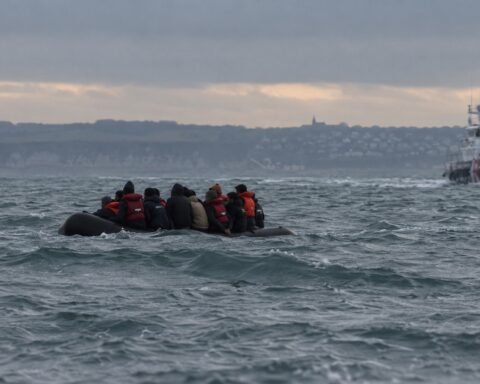 A small migrant boat in the English Channel with a rescue vessel nearby