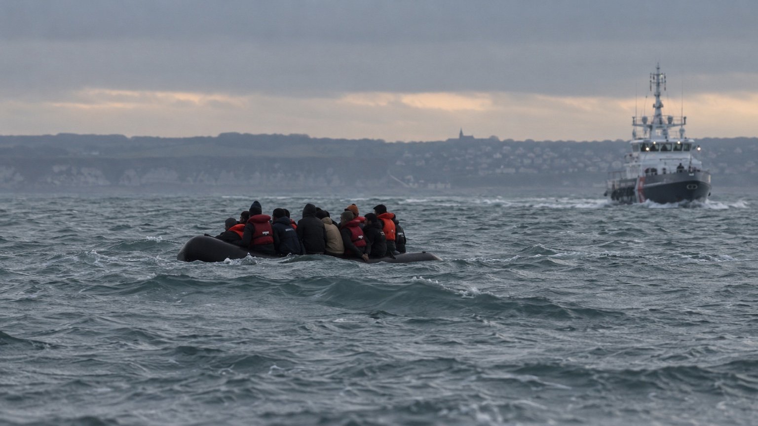 A small migrant boat in the English Channel with a rescue vessel nearby