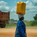 A woman carrying a yellow water container beside a road in Juba, South Sudan