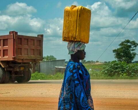 A woman carrying a yellow water container beside a road in Juba, South Sudan